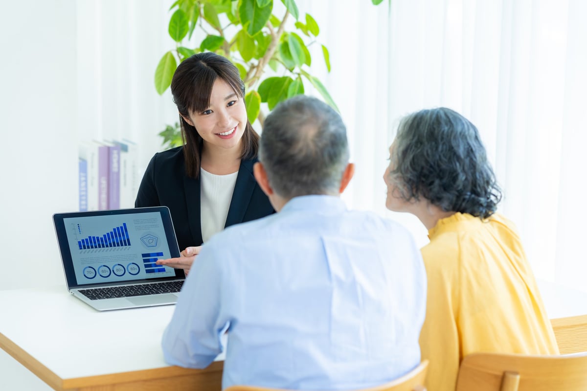An advisor talking with a senior couple across a table in a bright office