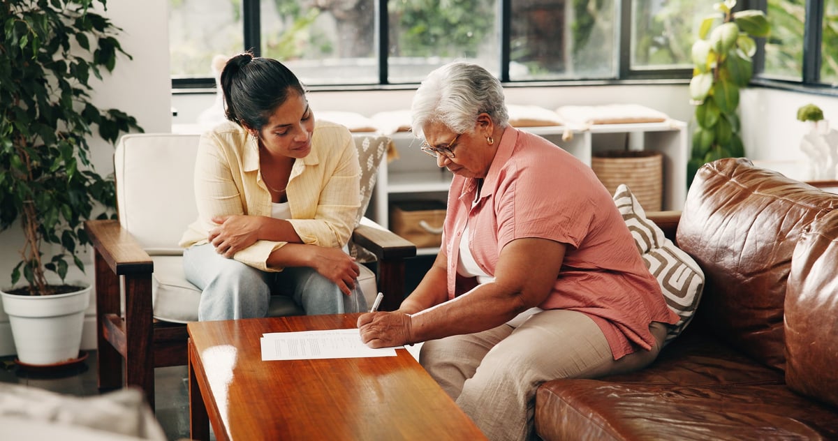 An adult daughter helping her elderly mother with paperwork at home
